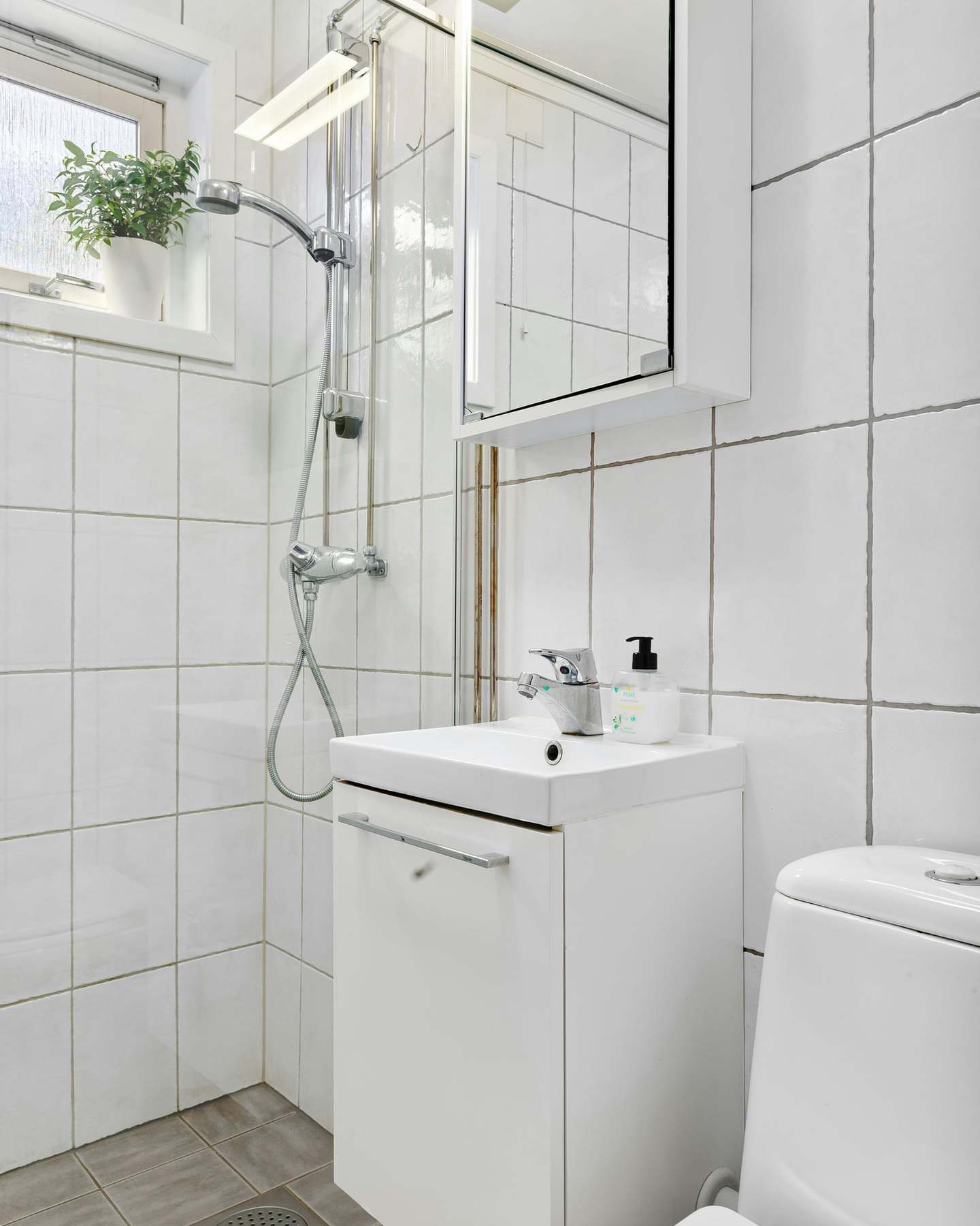 The shower room before the refit, with dated white tiles, stained grout and an old shower rail