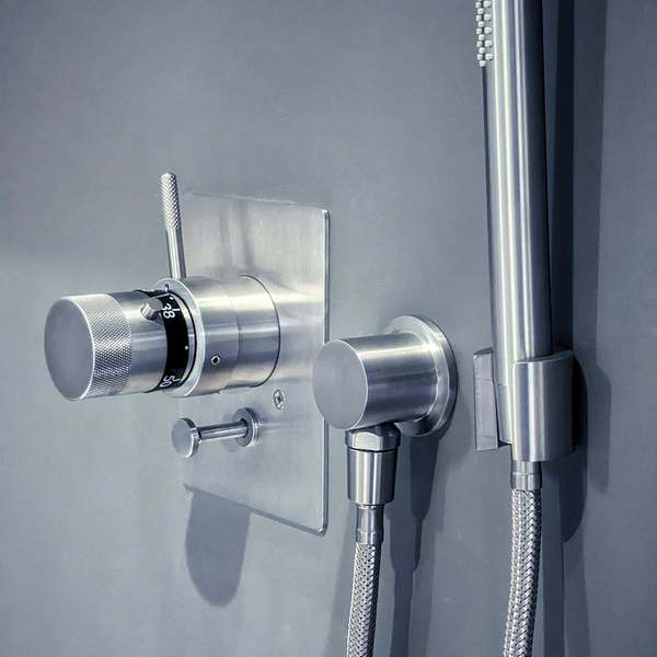 Brushed steel thermostatic shower valve and hand shower on a grey wall